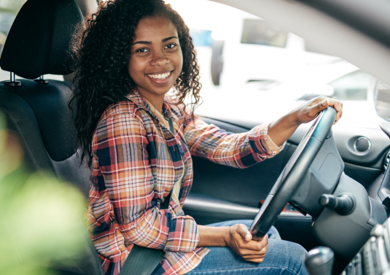 a smiling person is sitting in the driver's seat of a car