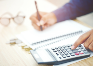 A person using a calculator and pen to write on paper